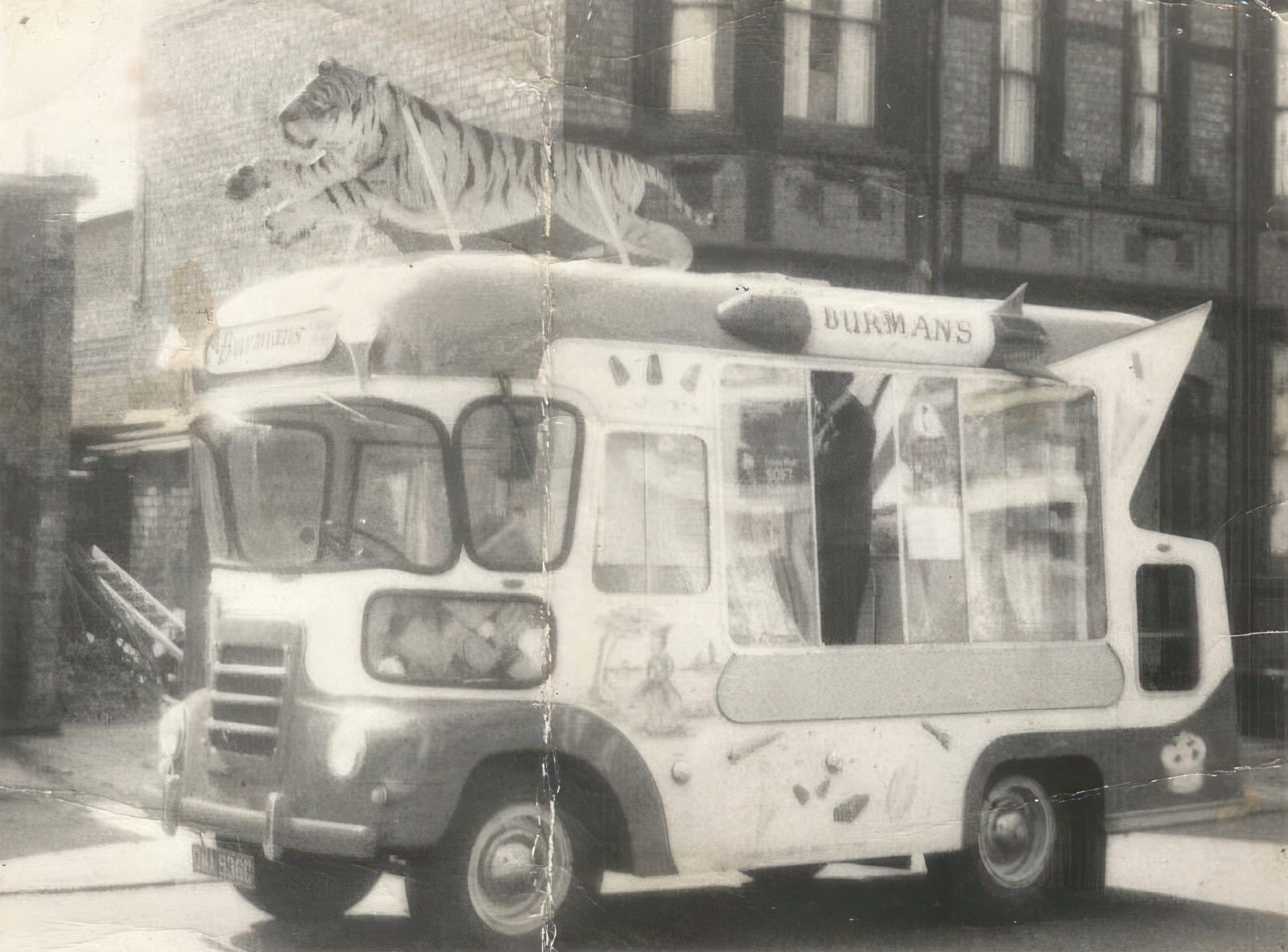 An old black and white photo showing an ice cream van with a large cut-out tiger on its roof