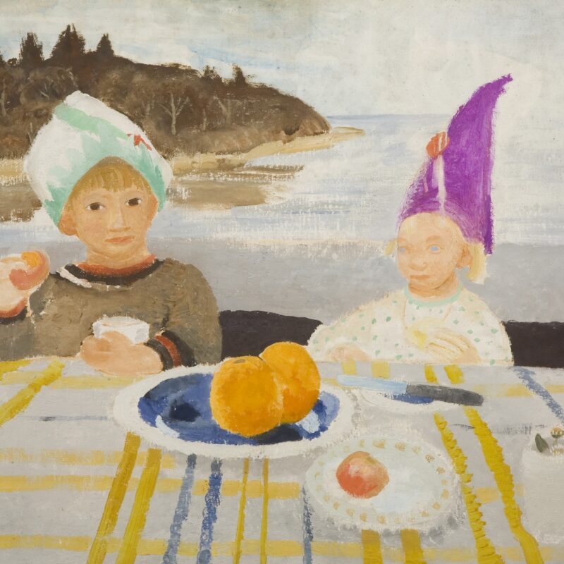 Two children eating at a table in front of a sea shore