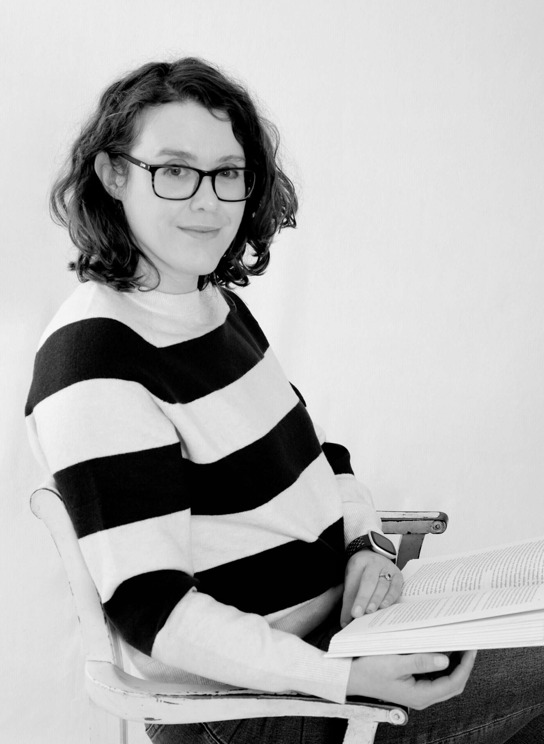 Helena Kelly in a stripey jumper holding a book