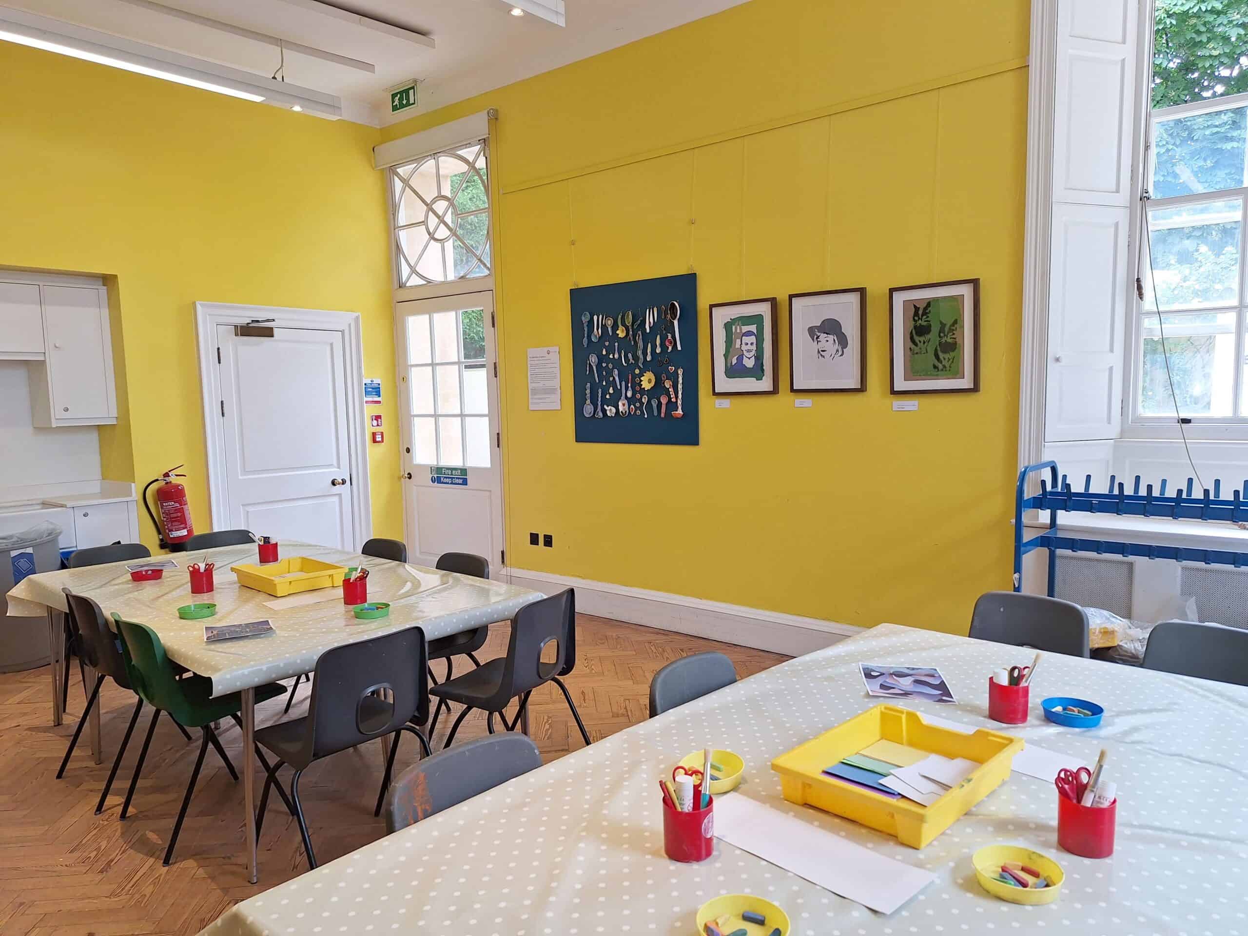 A yellow-walled room with tables set out with craft supplies