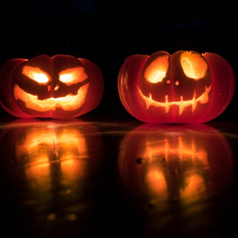 2 carved pumpkins lit up at night