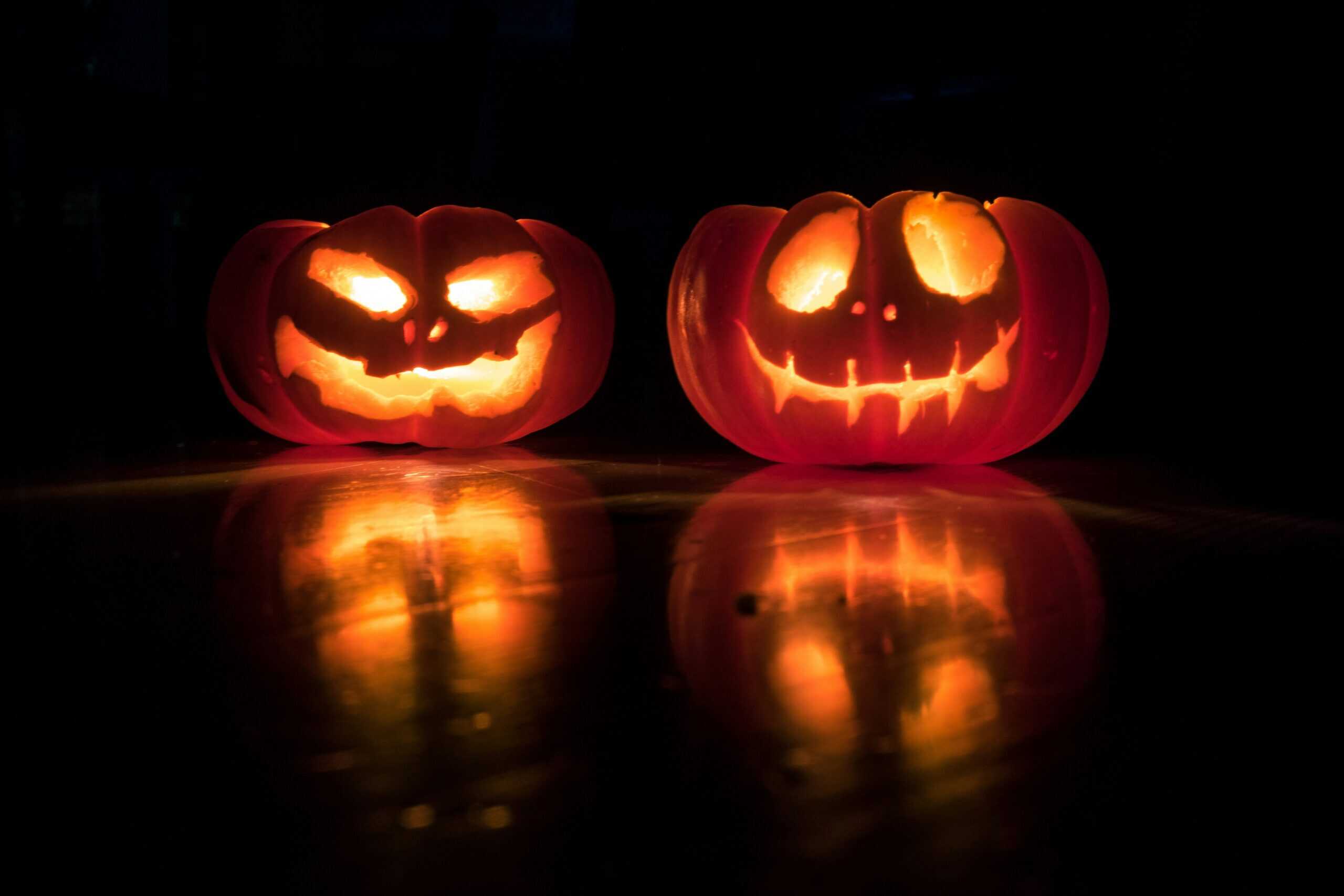 2 carved pumpkins lit up at night