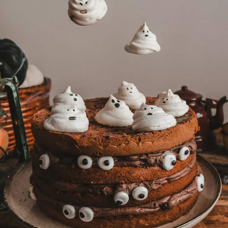 A large chocolate cake with floating confectionery ghosts above it and eyeballs on the side