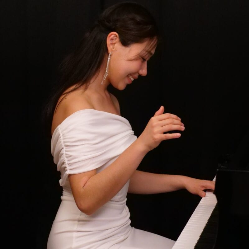 Nurry Lee in a white dress playing the piano