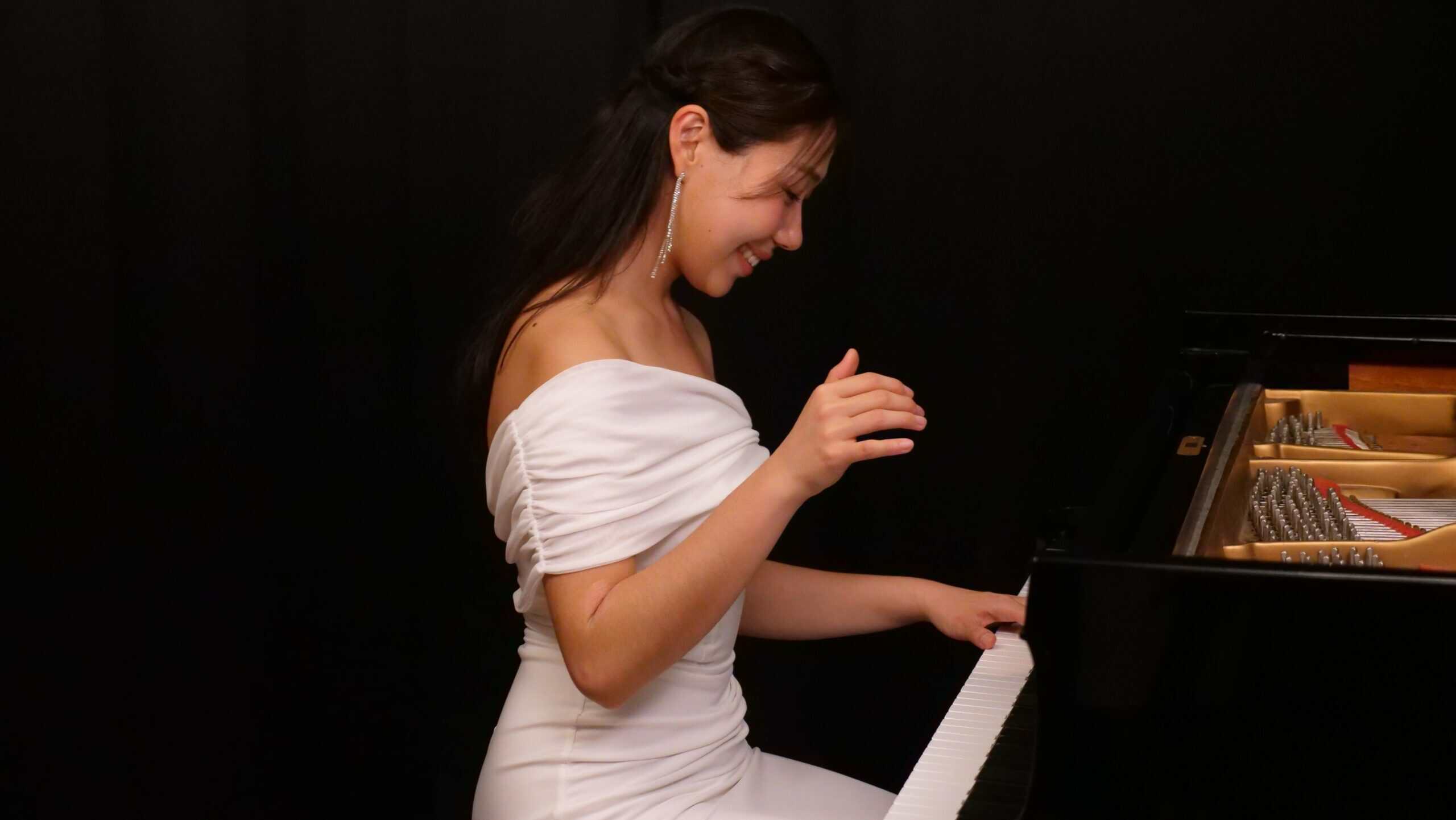 Nurry Lee in a white dress playing the piano
