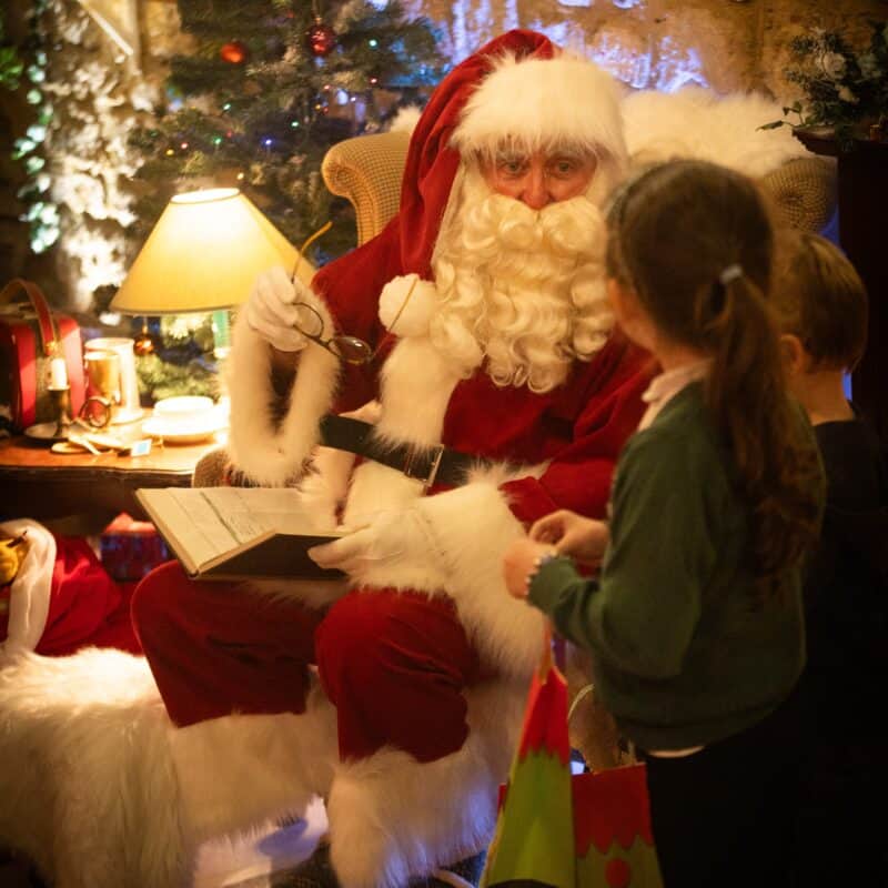 Man in red with big fluffy beard talking to child