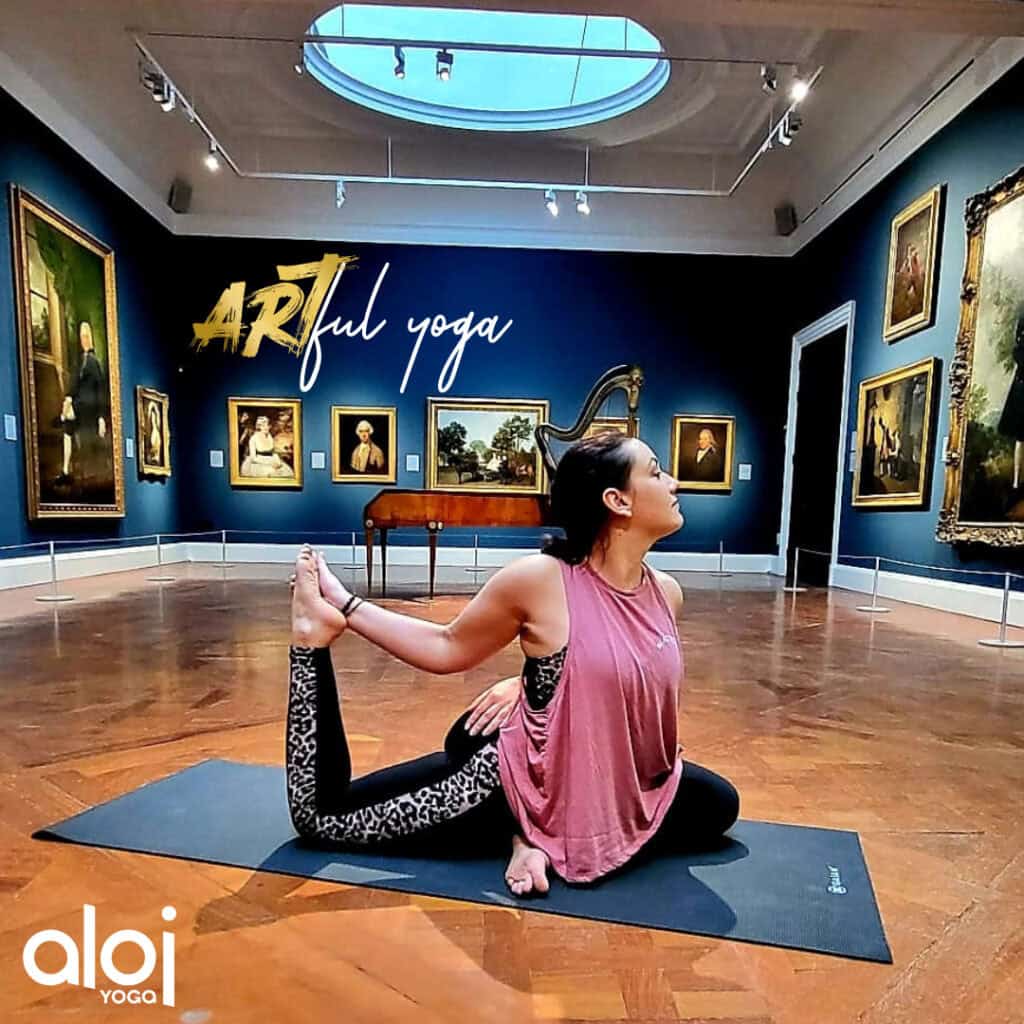 Woman with dark hair in pink doing yoga in art gallery.