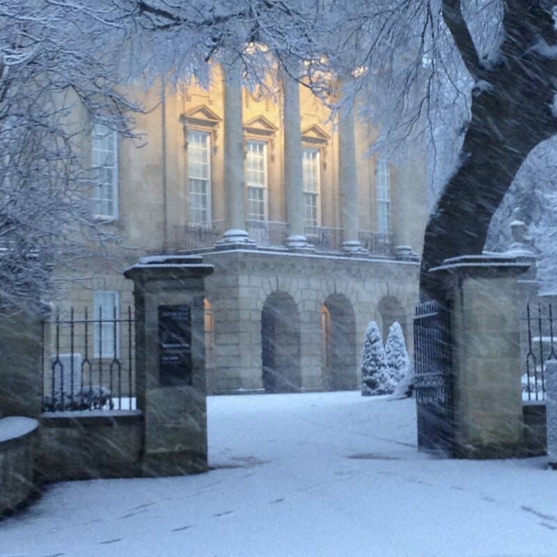 Front of museum building and gate posts covered in white snow
