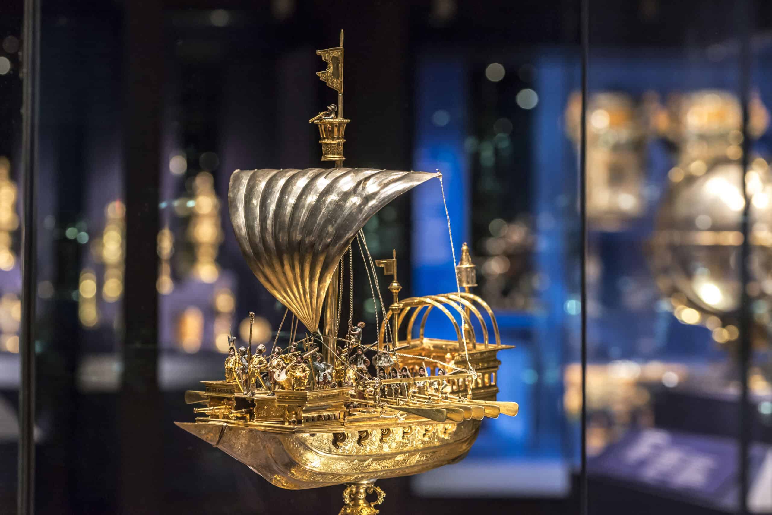 Photo of a gold coloured model ship with a silver sail and intricate figures