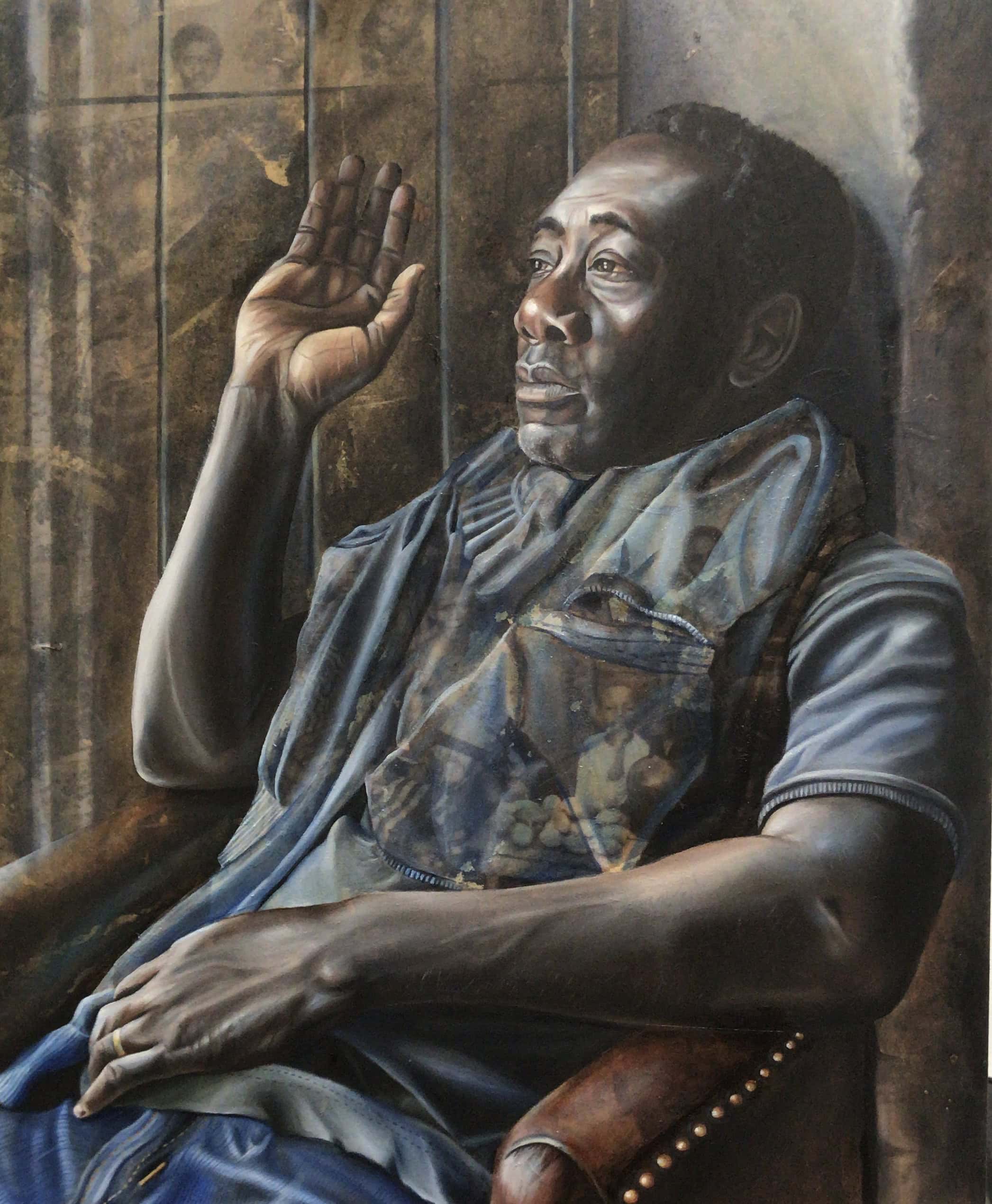 A man relaxing back in a chair with his right arm raised