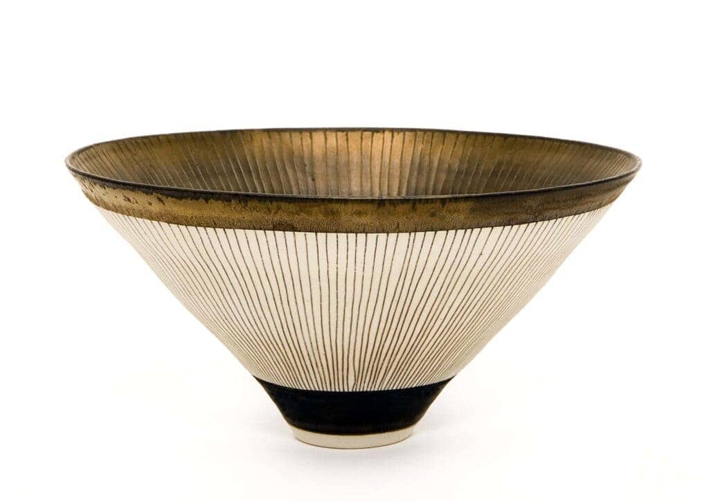 A white bowl with a black base, golden on the inside