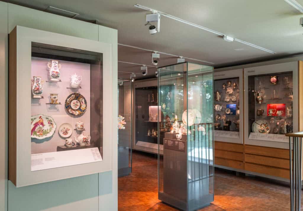 Photo showing a gallery with glass display cabinets showing decorative plates and figurines from the 18th century