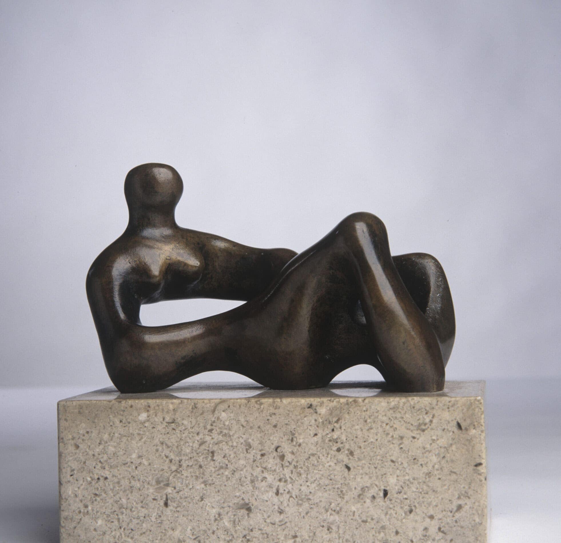 Bronze sculpture of a reclining man on a stone plinth