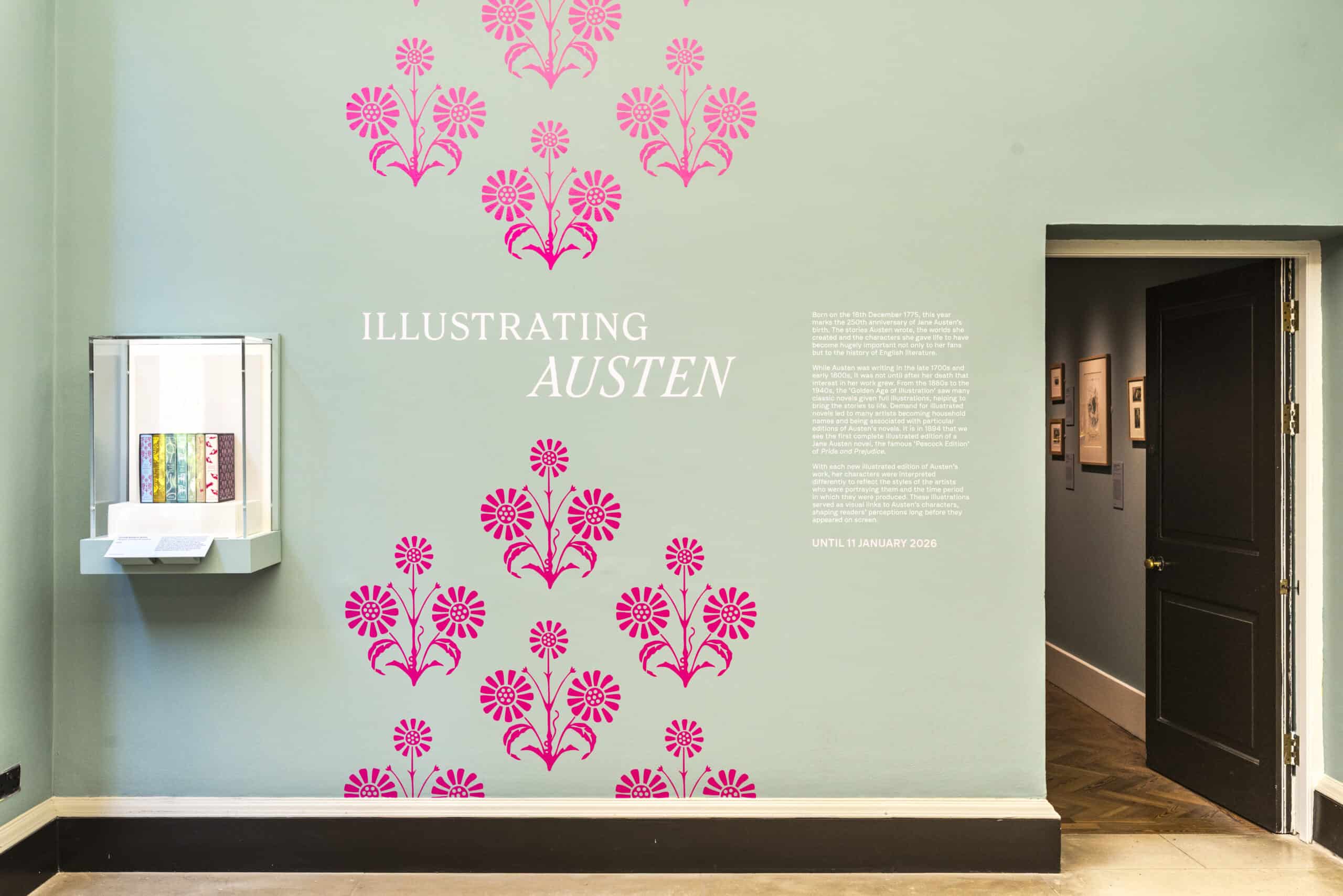 The outside wall of the Holburne's Illustrating Austen exhibition with pink flowers on a green wall
