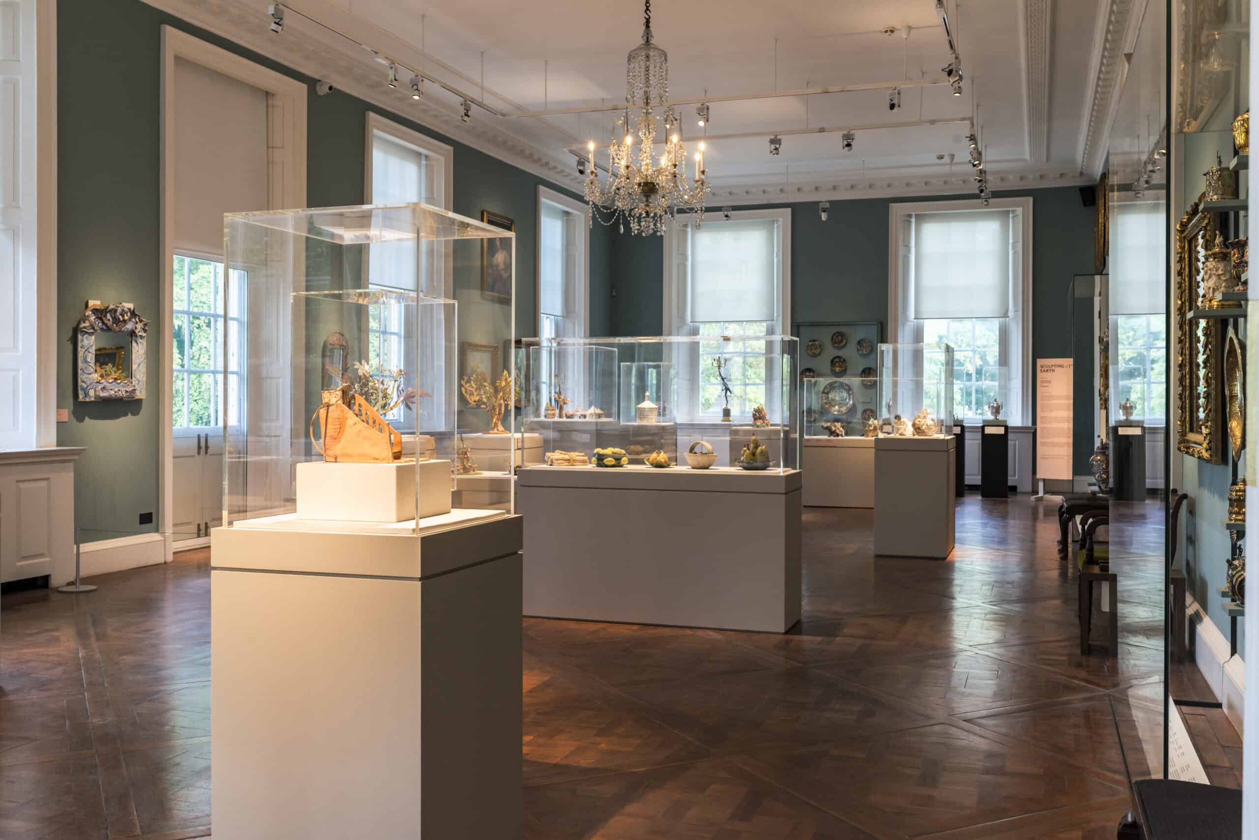 Many display cases holding clay sculptures in the Holburne ballroom