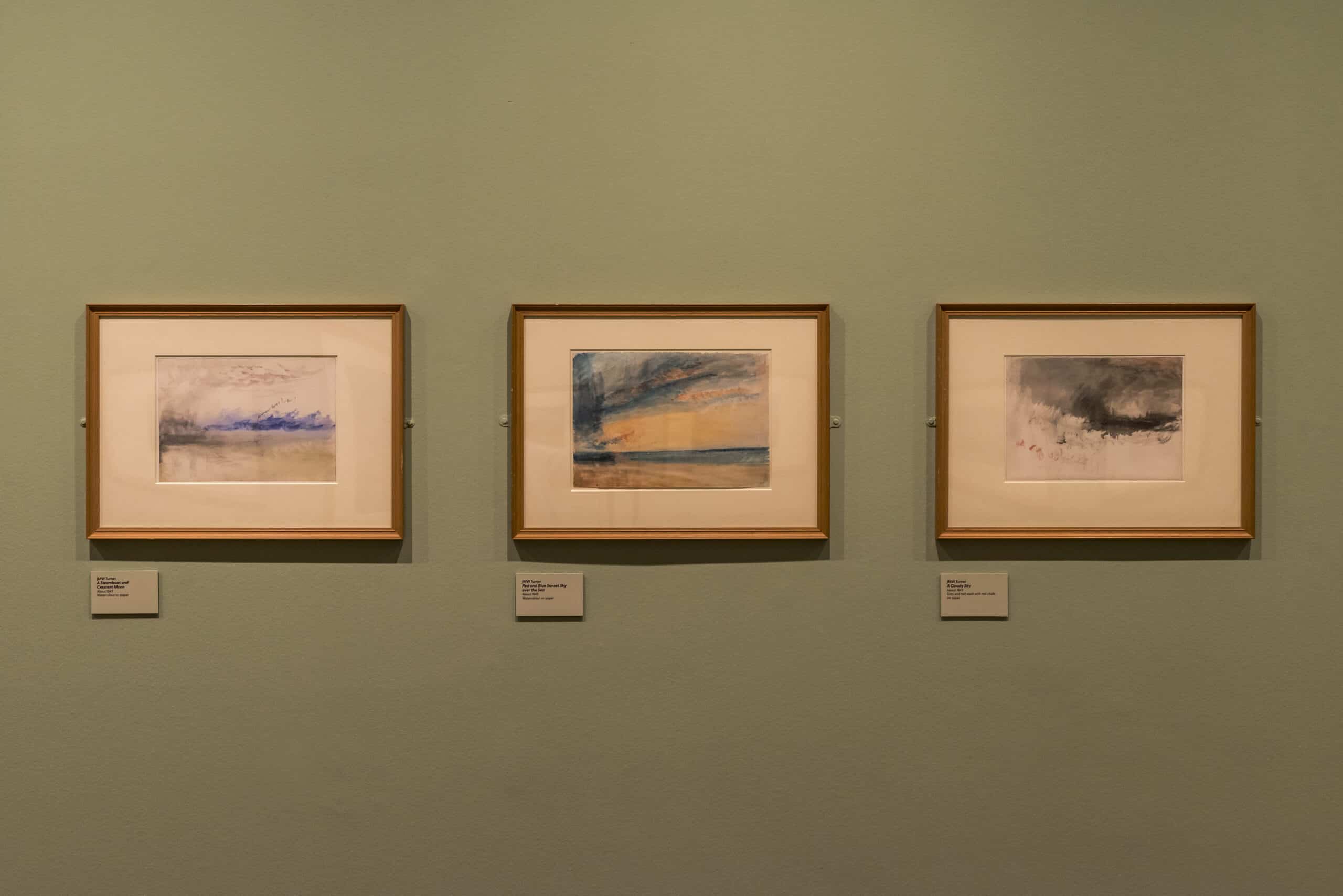 Three Turner watercolours in a line along a green wall