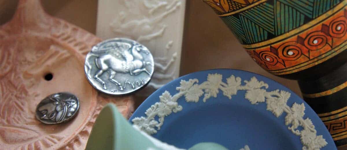 A selection of greek artifacts including a coin, vase and plate.