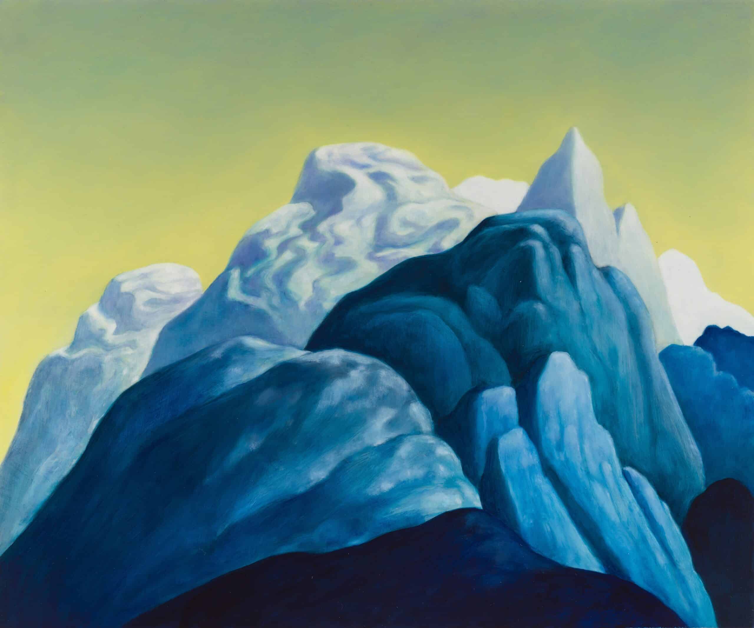 Different mountain peaks in various shades of blue against a greeny yellow sky