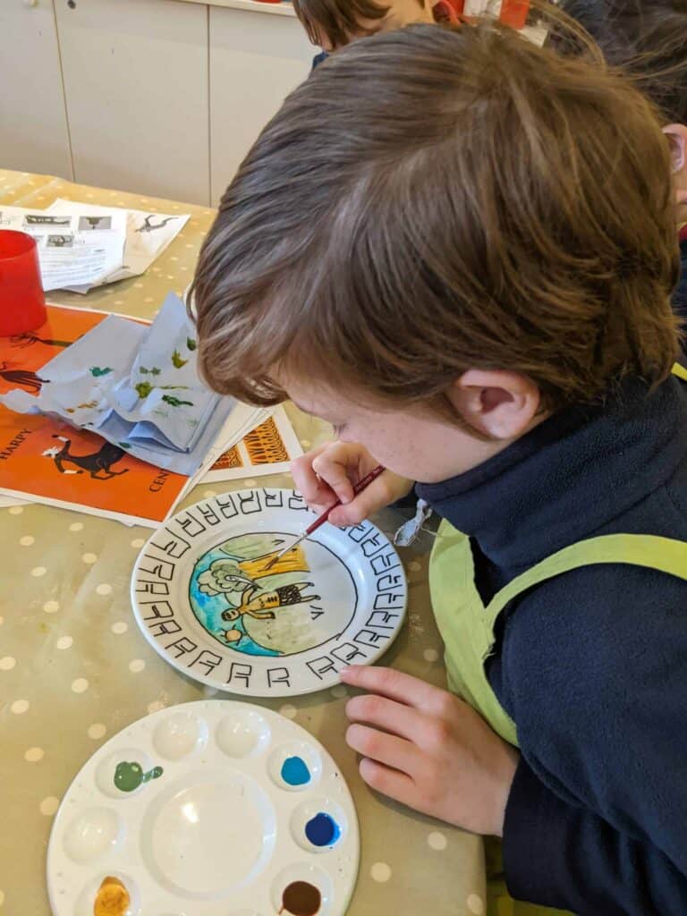 Boy painting a plate with ancient greek imagery.