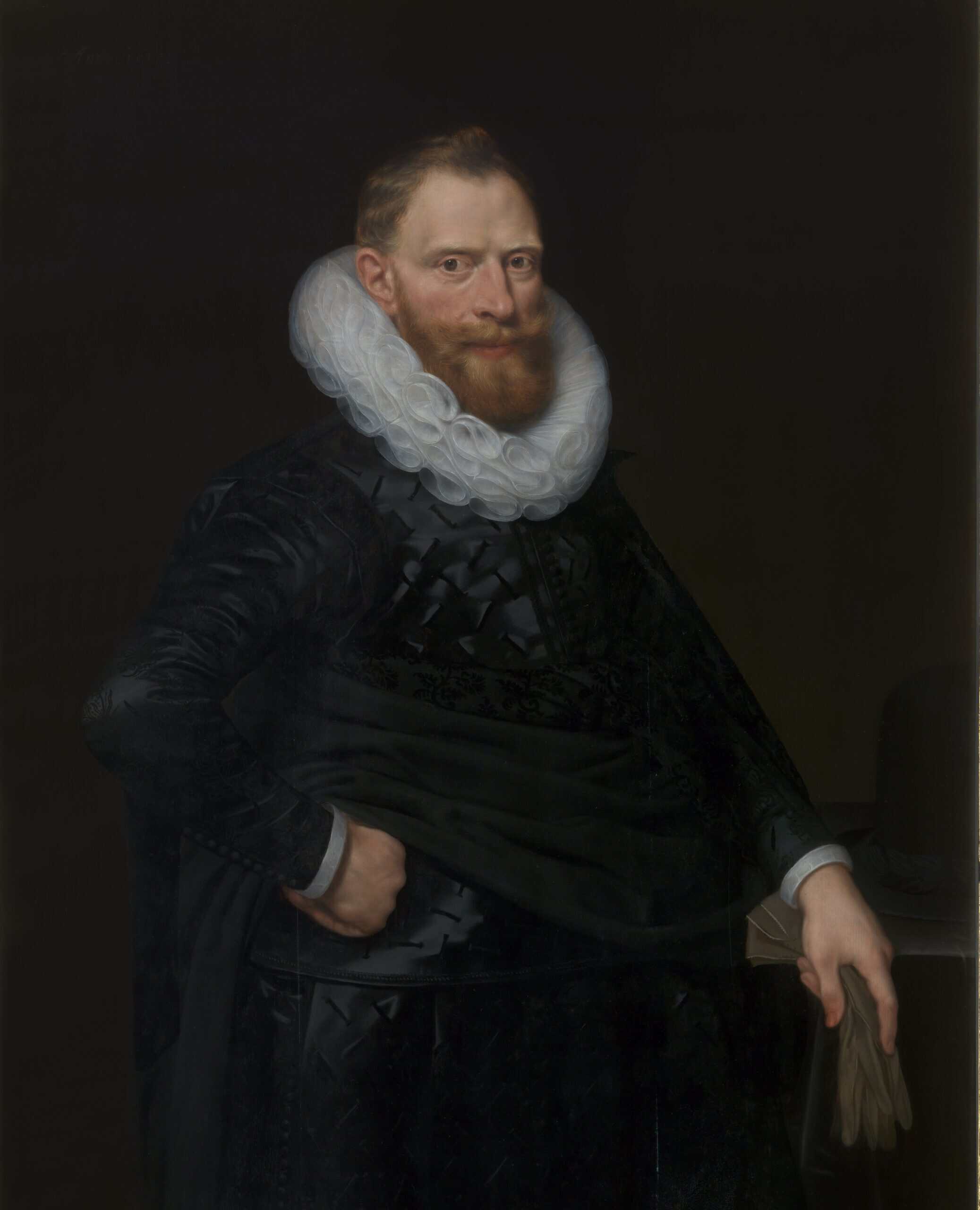 Painting of a man with red hair and beard in black costume with a white ruff around his neck. He stands with one hand on his hip, and holds a pair of leather gloves in his left hand.