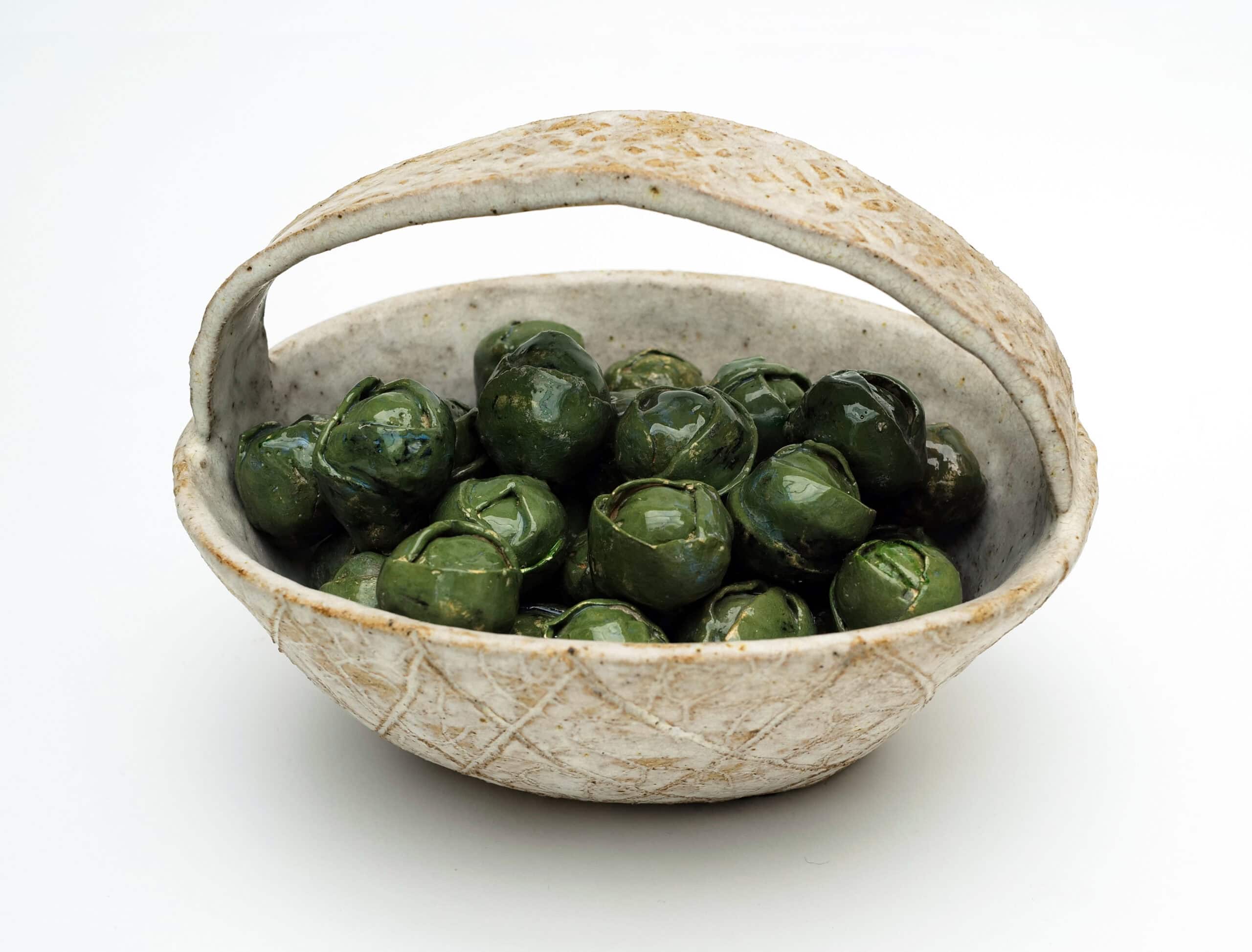 Green clay sprouts in a beige clay bowl