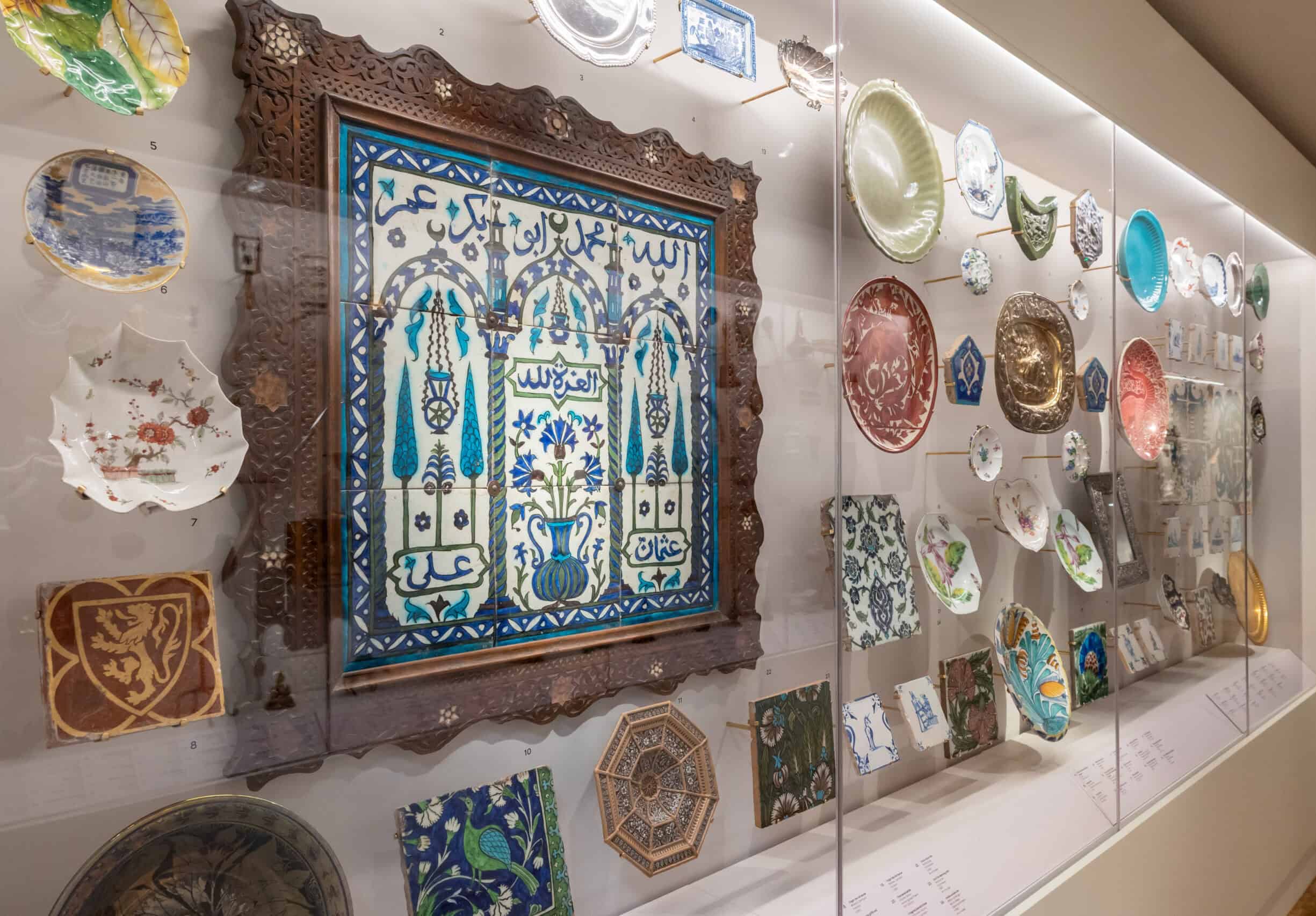 Display case in the Peckham Corridor exhibition featuring ceramics and decorative tiles from the Holburne Museum collection.