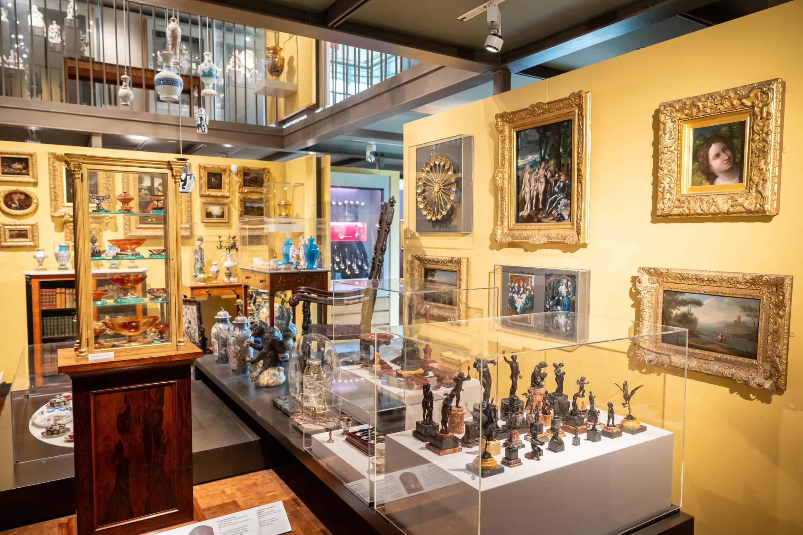 Photo showing a gallery packed with small decorative objects against yellow walls