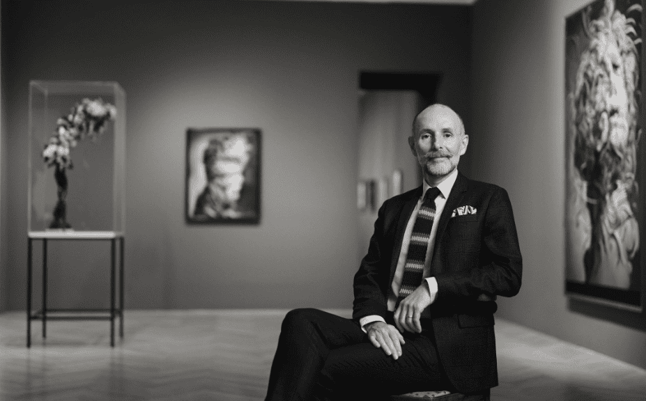 The artist Glenn Brown sitting in a chair in a black and white photo