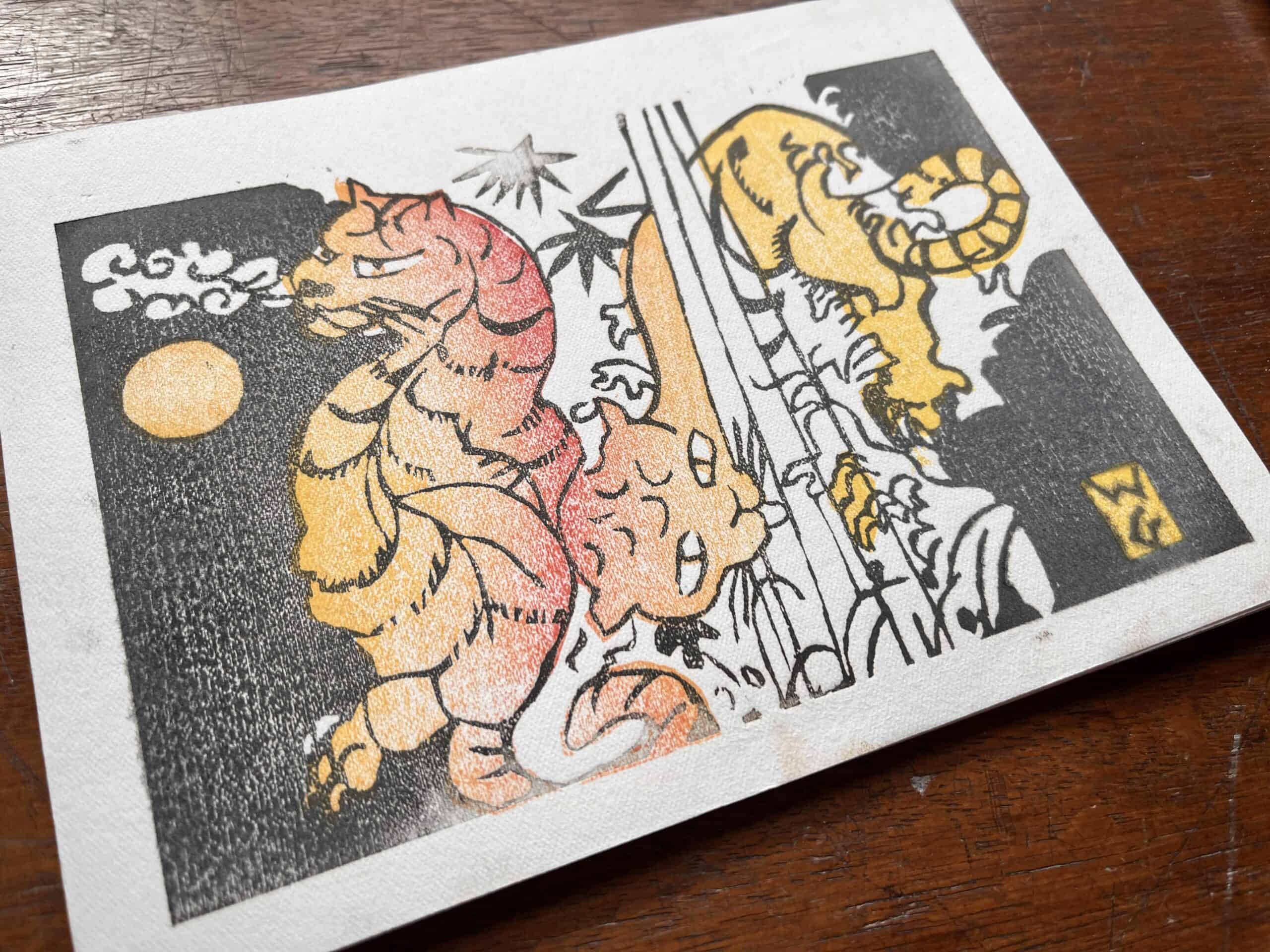A woodblock drawing on a table with tigers on it in orange and red