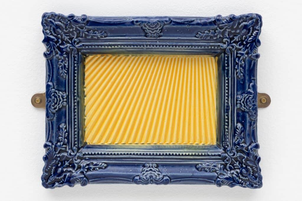 Photo showing a glazed ceramic blue picture frame, with yellow sun beams inside