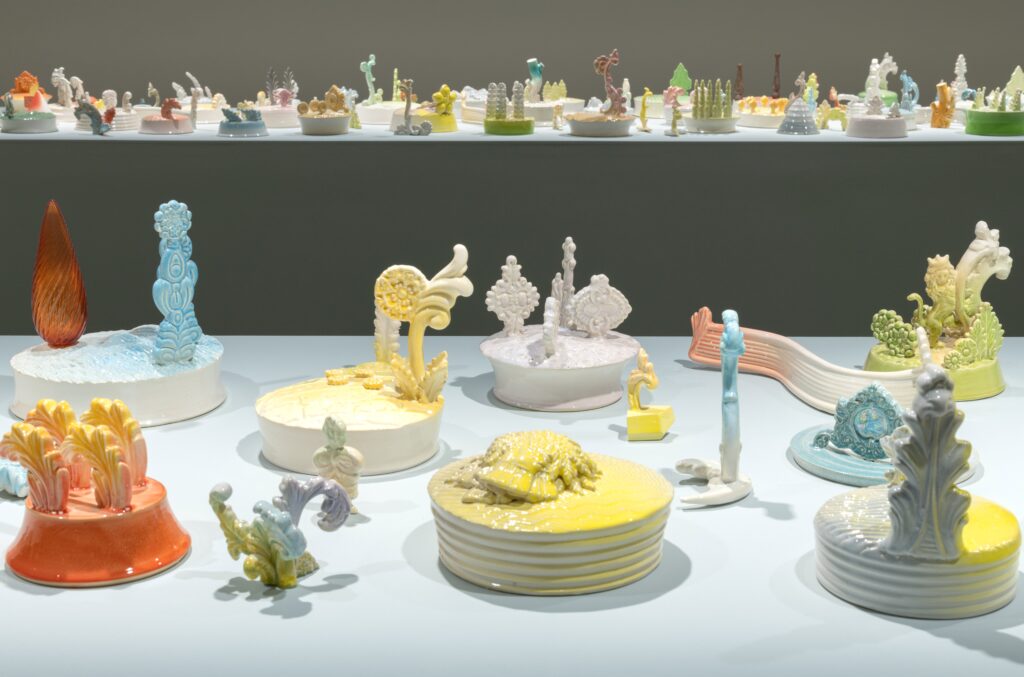 Photo showing a large number of small pastel coloured ceramic plinths installed on a white tabletop